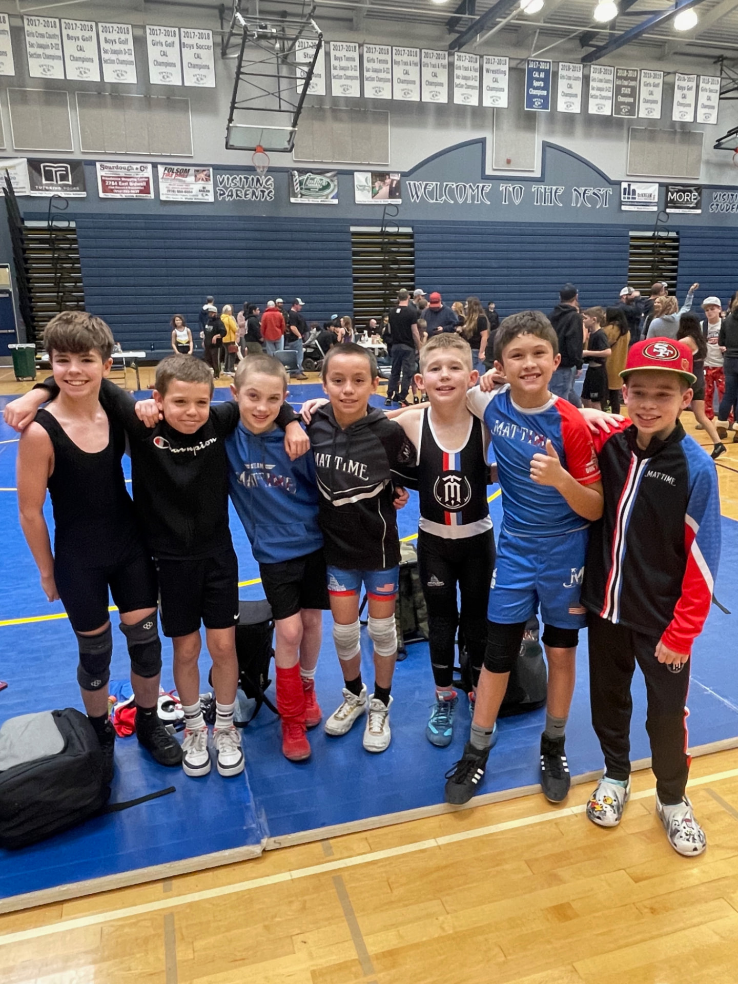Seven MatTime teammates standing together at a wrestling tournament