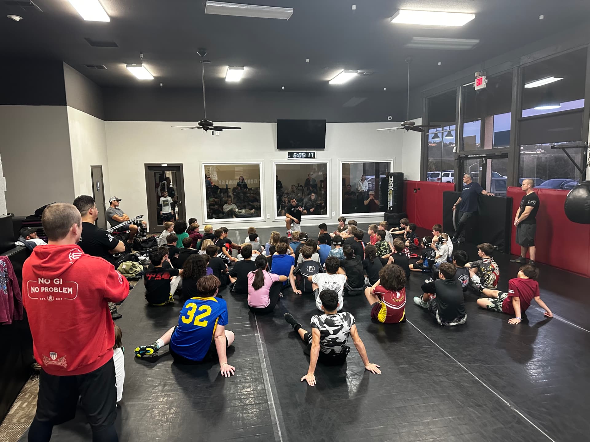 MatTime wrestlers seated on the mat listening to a coach before practice