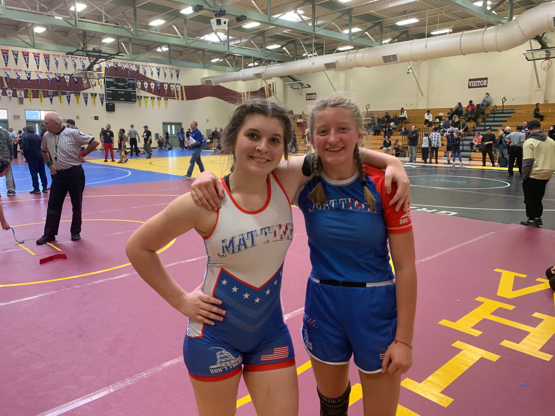 Two smiling MatTime girl wrestlers posing together at a tournament